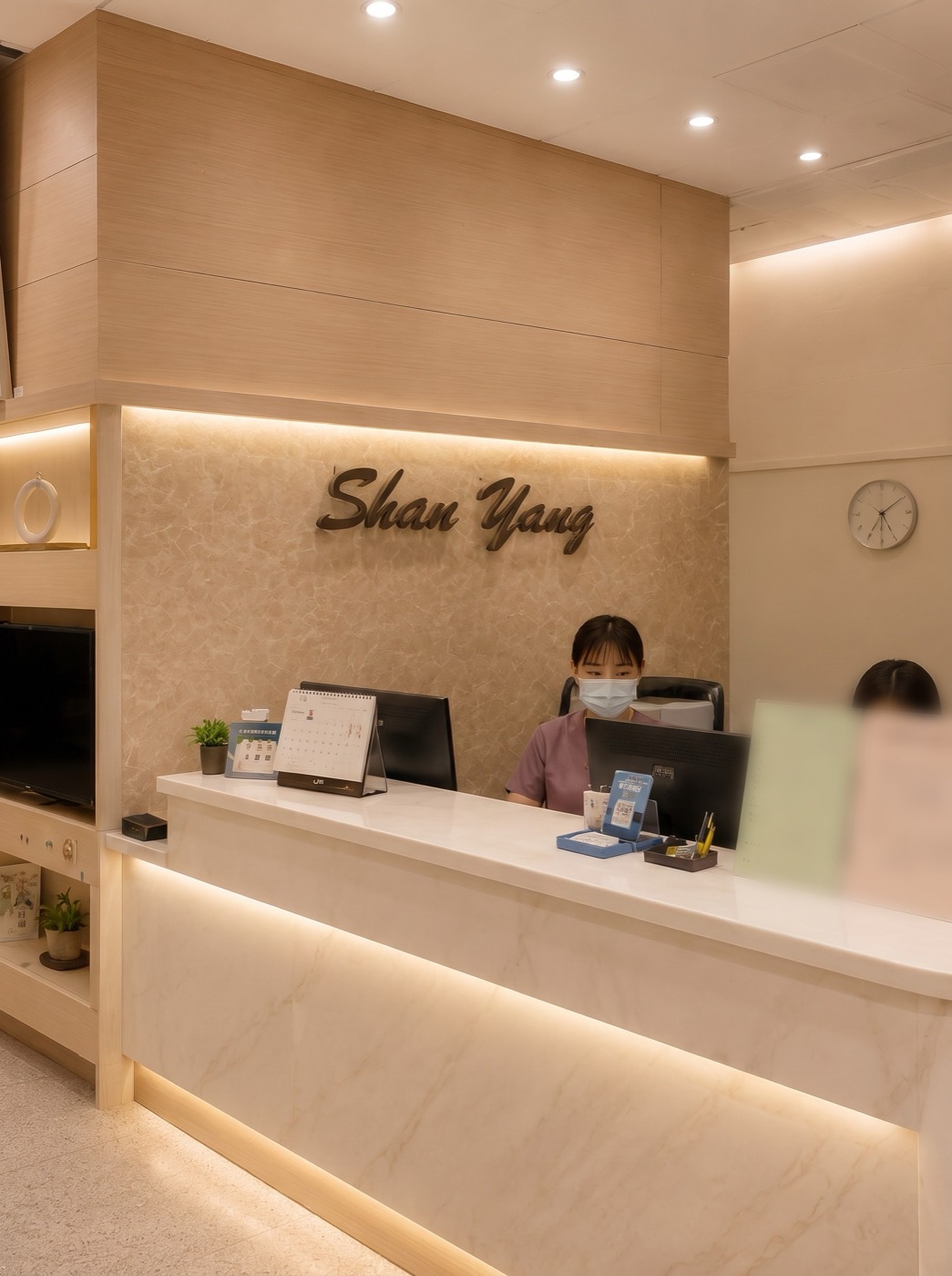 向陽牙醫接待櫃檯實景，溫暖的木質空間與 Shan Yang 招牌